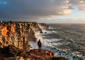 Senderista solitario en los acantilados del Cabo de São Vicente contemplando el océano Atlántico en Portugal