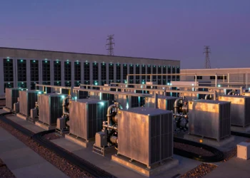 Centro de datos moderno al atardecer con pilas de combustible de hidrógeno y torres eléctricas desconectadas al fondo