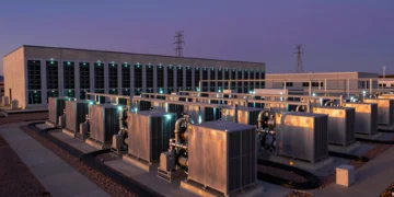 Centro de datos moderno al atardecer con pilas de combustible de hidrógeno y torres eléctricas desconectadas al fondo