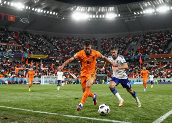 Jugador de Países Bajos con camiseta naranja disputa el balón ante un defensa japonés en el Mundial