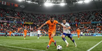 Jugador de Países Bajos con camiseta naranja disputa el balón ante un defensa japonés en el Mundial