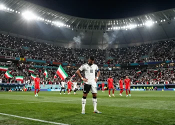 Jugador de Nueva Zelanda cabizbajo en el campo mientras jugadores de Irán celebran al fondo en el Mundial 2026