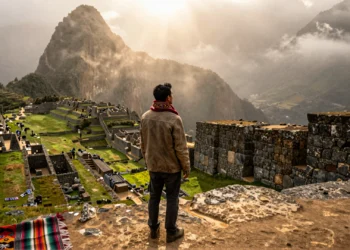 Viajero contemplando un valle neblinoso desde una terraza de piedra inca en los Andes peruanos al atardecer
