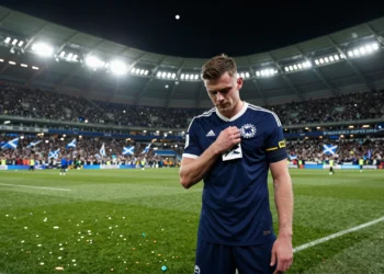 Andy Robertson con el brazalete de capitán de Escocia, cabizbajo en señal de duelo y determinación en un estadio lleno