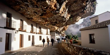 Casas blancas esculpidas en la roca arenisca de Setenil de las Bodegas, Cádiz, con vecinos paseando bajo el saliente natural