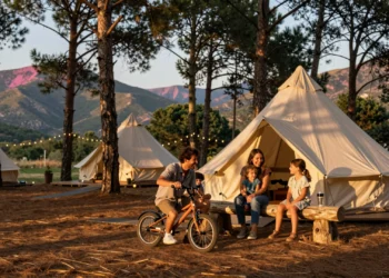 Familia española disfrutando de un glamping moderno entre pinos mediterráneos al atardecer en la Sierra española