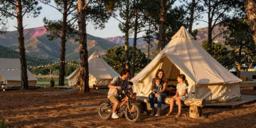 Familia española disfrutando de un glamping moderno entre pinos mediterráneos al atardecer en la Sierra española