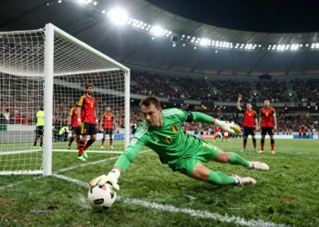 Portero iraní de verde se estira para desviar un disparo bajo los focos del estadio ante Bélgica