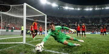 Portero iraní de verde se estira para desviar un disparo bajo los focos del estadio ante Bélgica