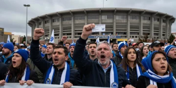 Aficionados del Deportivo con bufandas azules y blancas protestan frente al estadio sosteniendo pancartas y abonos
