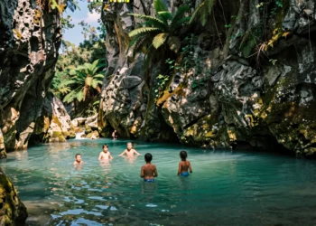 Grupo de personas refrescándose en una poza natural de agua turquesa en un estrecho cañón de roca caliza en Cataluña