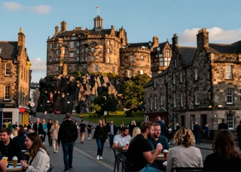 Royal Mile de Edimburgo en verano con el Castillo al fondo, fachadas de piedra bañadas por luz dorada y ambiente festivo