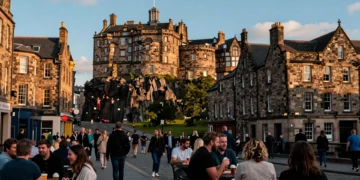 Royal Mile de Edimburgo en verano con el Castillo al fondo, fachadas de piedra bañadas por luz dorada y ambiente festivo