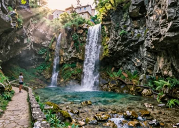 Cascada de doble salto en las gargantas del Pirineo aragonés con poza turquesa y senderista en primer plano