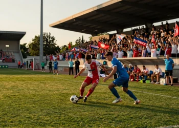 Dos futbolistas disputan un balón en un partido de pretemporada europea bajo la luz dorada de una tarde de julio