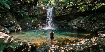 Bañista en una piscina natural de roca granítica rodeada de bosque verde y cascada en el norte de España