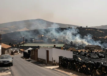 Pueblo andaluz rodeado de colinas calcinadas tras un devastador incendio forestal, con calles vacías y cielo cubierto de humo