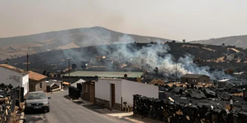 Pueblo andaluz rodeado de colinas calcinadas tras un devastador incendio forestal, con calles vacías y cielo cubierto de humo