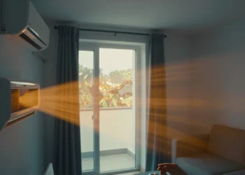 Aire acondicionado en sala de estar con contraste visual entre interior frío azulado y calor exterior anaranjado en verano