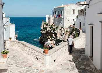 Callejón medieval de piedra blanca en Vieste, Puglia, con vistas al mar Adriático desde lo alto del acantilado