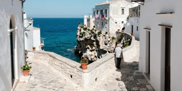Callejón medieval de piedra blanca en Vieste, Puglia, con vistas al mar Adriático desde lo alto del acantilado