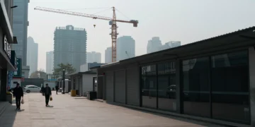 Calle comercial vacía en ciudad china con negocios cerrados, grúa inactiva y peatones bajo cielo gris nublado
