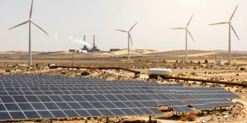 Paneles solares y aerogeneradores junto a un camión cisterna de gas en una llanura castellana bajo el sol mediterráneo