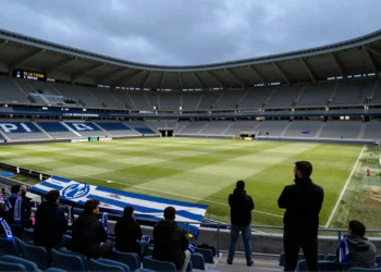 Grada de animación del estadio de Riazor semivacía con bufandas y tifo azul y blanco en la barandilla bajo luz gris atlántica