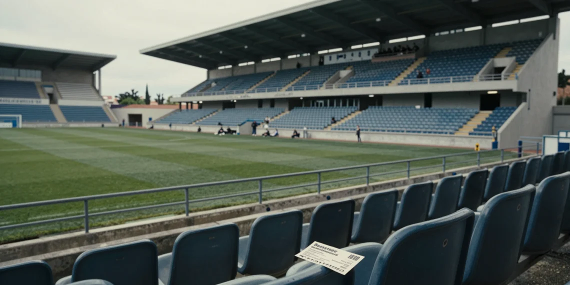 Gradas casi vacías del estadio del Lorca Deportiva con un abono de temporada arrugado sobre un asiento de plástico