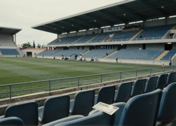 Gradas casi vacías del estadio del Lorca Deportiva con un abono de temporada arrugado sobre un asiento de plástico