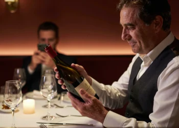 Sumiller experimentado examina una botella de vino con reverencia en restaurante con estrella Michelin de Barcelona