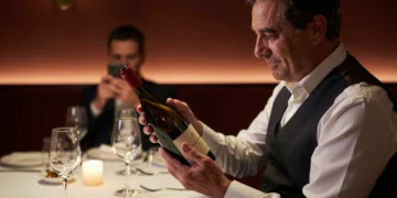 Sumiller experimentado examina una botella de vino con reverencia en restaurante con estrella Michelin de Barcelona