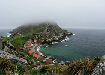 Costa atlántica de las Rías Altas de Galicia con acantilados de granito, aldea pesquera y barca solitaria en aguas esmeralda