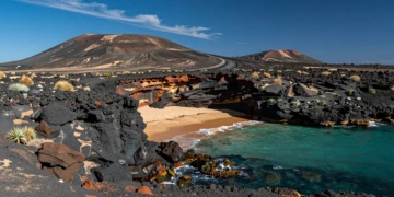 Costa volcánica del Parque Natural Cabo de Gata-Níjar con rocas negras, aguas turquesas y playa virgen de arena dorada