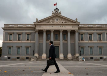 Congreso de los Diputados en Madrid bajo cielo gris otoñal con hojas caídas y funcionario cruzando la plaza