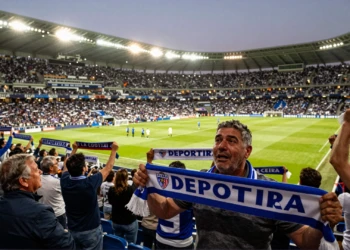 Aficionado del Deportivo de La Coruña emocionado con bufanda azul y blanca en estadio lleno en el regreso a LaLiga