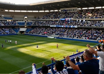 Aficionados del Huesca con bufandas azules y blancas en el estadio en el regreso al fútbol semiprofesional
