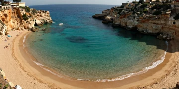 Vista aérea de Cala Cortina, bahía mediterránea de aguas turquesas con acantilados dorados junto a Cartagena