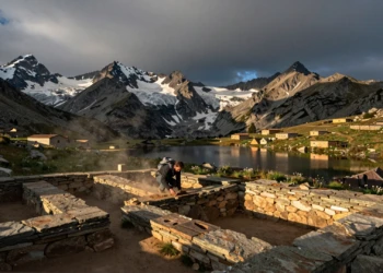 Arqueólogo excavando artefactos prehistóricos junto a un lago glaciar en los Pirineos catalanes al atardecer