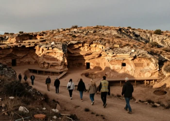 Visitantes y arqueólogo recorriendo las trincheras de excavación de Atapuerca, Burgos, al atardecer