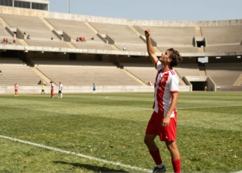 Jugador de fútbol catalán celebra un gol en partido de pretemporada en estadio municipal bajo el sol de agosto