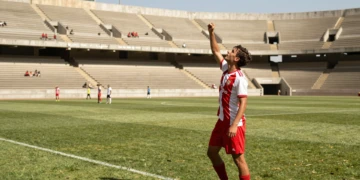 Jugador de fútbol catalán celebra un gol en partido de pretemporada en estadio municipal bajo el sol de agosto