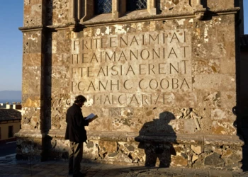 Historiador examina inscripción latina medieval en la fachada del Barrio Gótico de Barcelona al atardecer