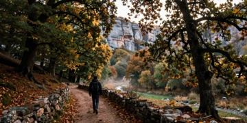 Senderista solitario en un sendero de piedra entre robles y hayas en el Valle de Valdivielso, Burgos