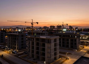 Obras de construcción residencial en Murcia al atardecer con bloques sin luz eléctrica y grúas bajo cielo naranja