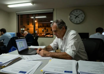 Funcionario español trabaja de madrugada sobre documentos de fondos europeos con reloj marcando la urgencia