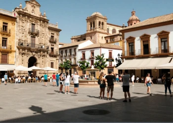 Plaza barroca de Murcia llena de turistas y locales en verano, con terrazas de cafés y fachadas doradas al sol
