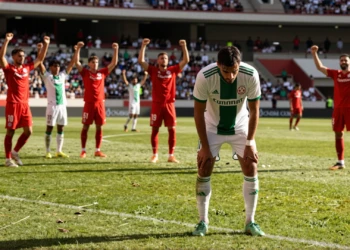 Jugador del Córdoba CF exhausto en el césped mientras el Almería celebra al fondo en pretemporada en Marbella