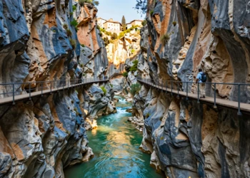 Senderista en pasarela suspendida sobre el cañón del río Vero, con paredes de caliza y aguas esmeraldas en Aragón