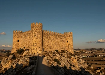 Castillo medieval de piedra dorada en lo alto de una colina árida de Murcia bajo un cielo azul cobalto al atardecer